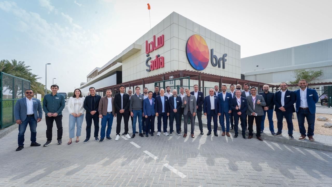 A group of about thirty people posing in front of a building bearing the Sadia and BRF signs